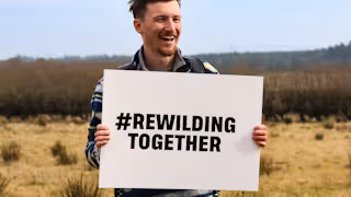Man holding rewilding together sign