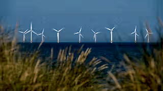 Scroby Sands Wind Farm located in the North Sea off Norfolk coast in the distance, photographed through the grassy sand dunes at Caister on Sea near Great Yarmouth, Norfolk UK.